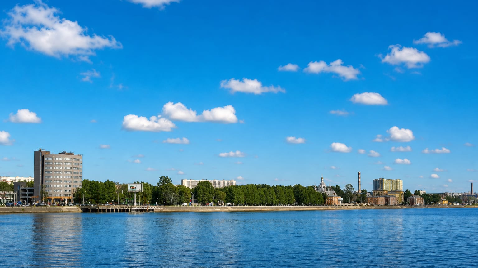 Waterfront across the Neva showing a tower block, an Orthodox church and an industrial chimney in Krasnogvardeysky, Saint Petersburg.