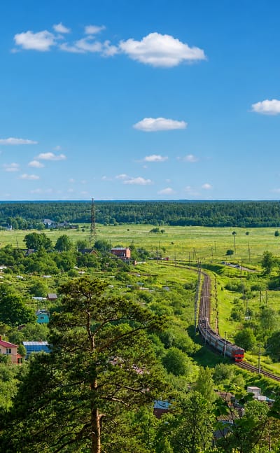 Elevated view over green suburban houses and a railway curving through fields near Krasnoye Selo, Saint Petersburg.