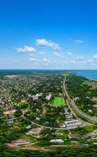Aerial view of low-rise Tarkhovka, St. Petersburg, set between a lake and the Gulf of Finland shore amid dense forest
