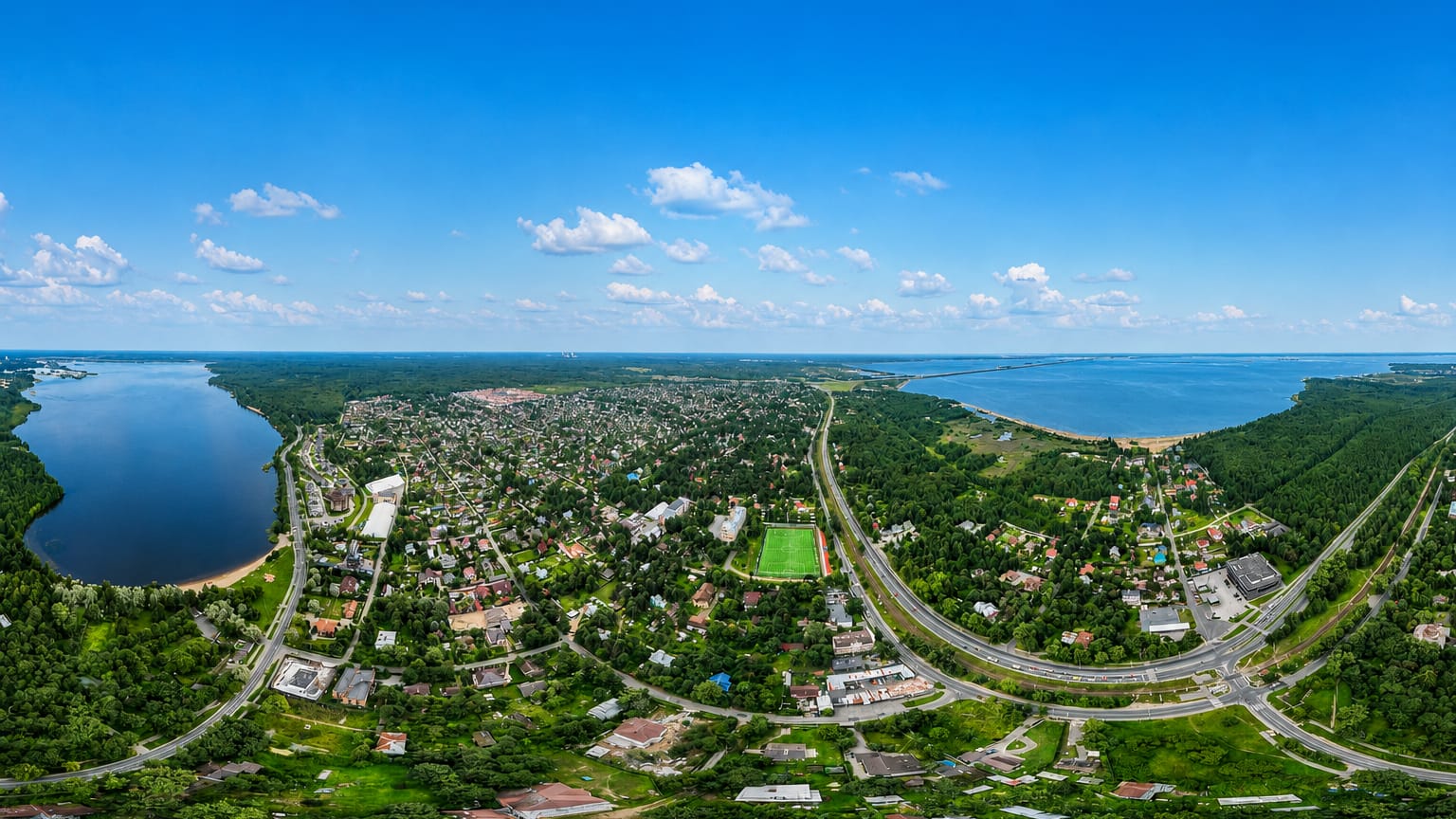 Aerial view of low-rise Tarkhovka, St. Petersburg, set between a lake and the Gulf of Finland shore amid dense forest