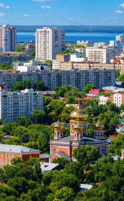 Aerial view of Saratov with a golden-domed Orthodox church, apartment blocks and the Volga River beyond.