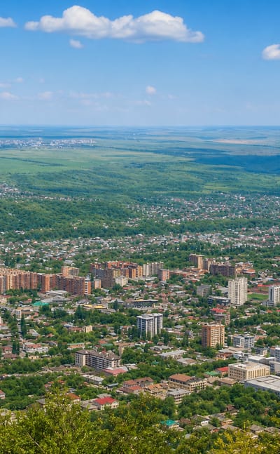 Elevated panorama of Pyatigorsk spreading across green wooded hills and plains.