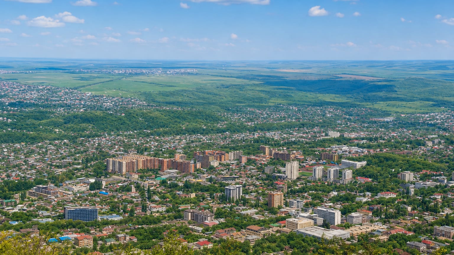 Elevated panorama of Pyatigorsk spreading across green wooded hills and plains.