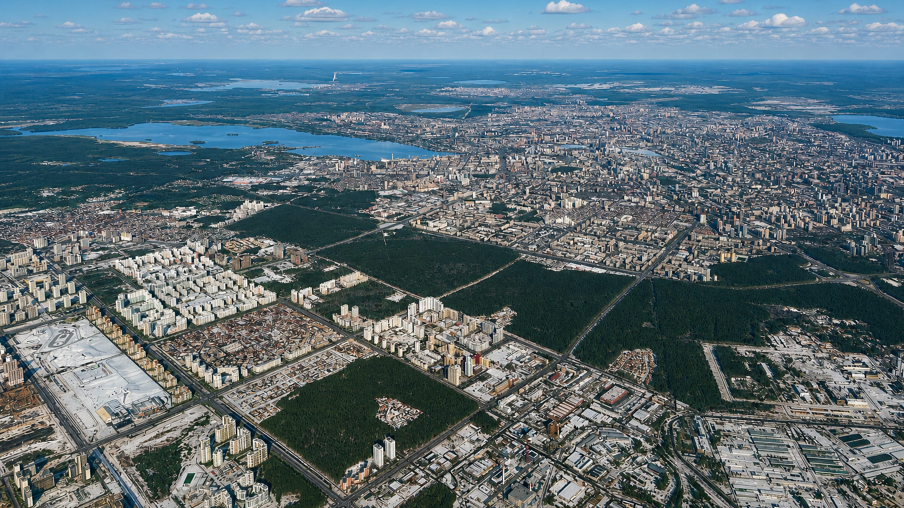 High aerial over Yekaterinburg, with the Akademicheskiy district's housing blocks beside forest and city lakes.