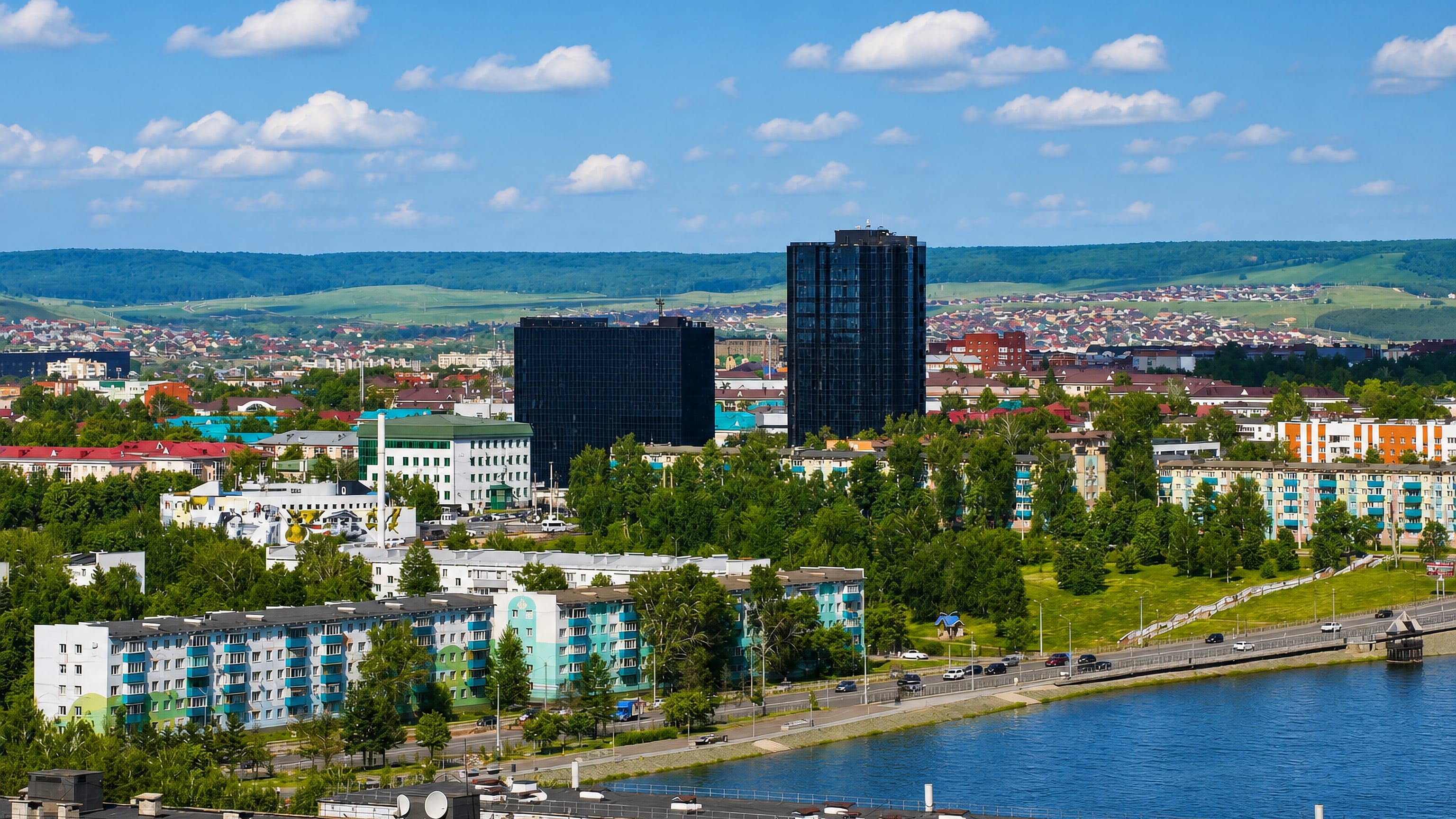 Almetyevsk, Tatarstan, seen across its riverside embankment, with dark glass towers above low Soviet-era blocks.