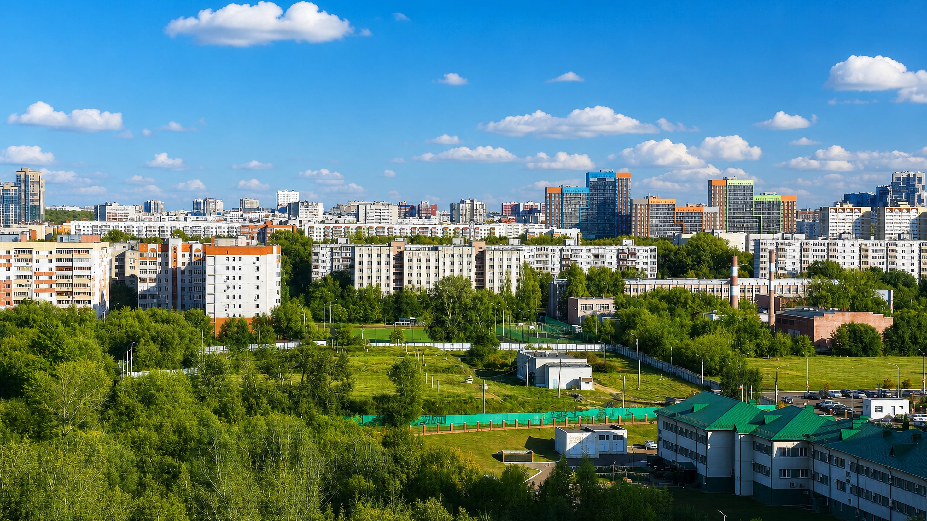 Soviet-era apartment blocks and green courtyards across the Gorki district of Kazan under a summer sky.