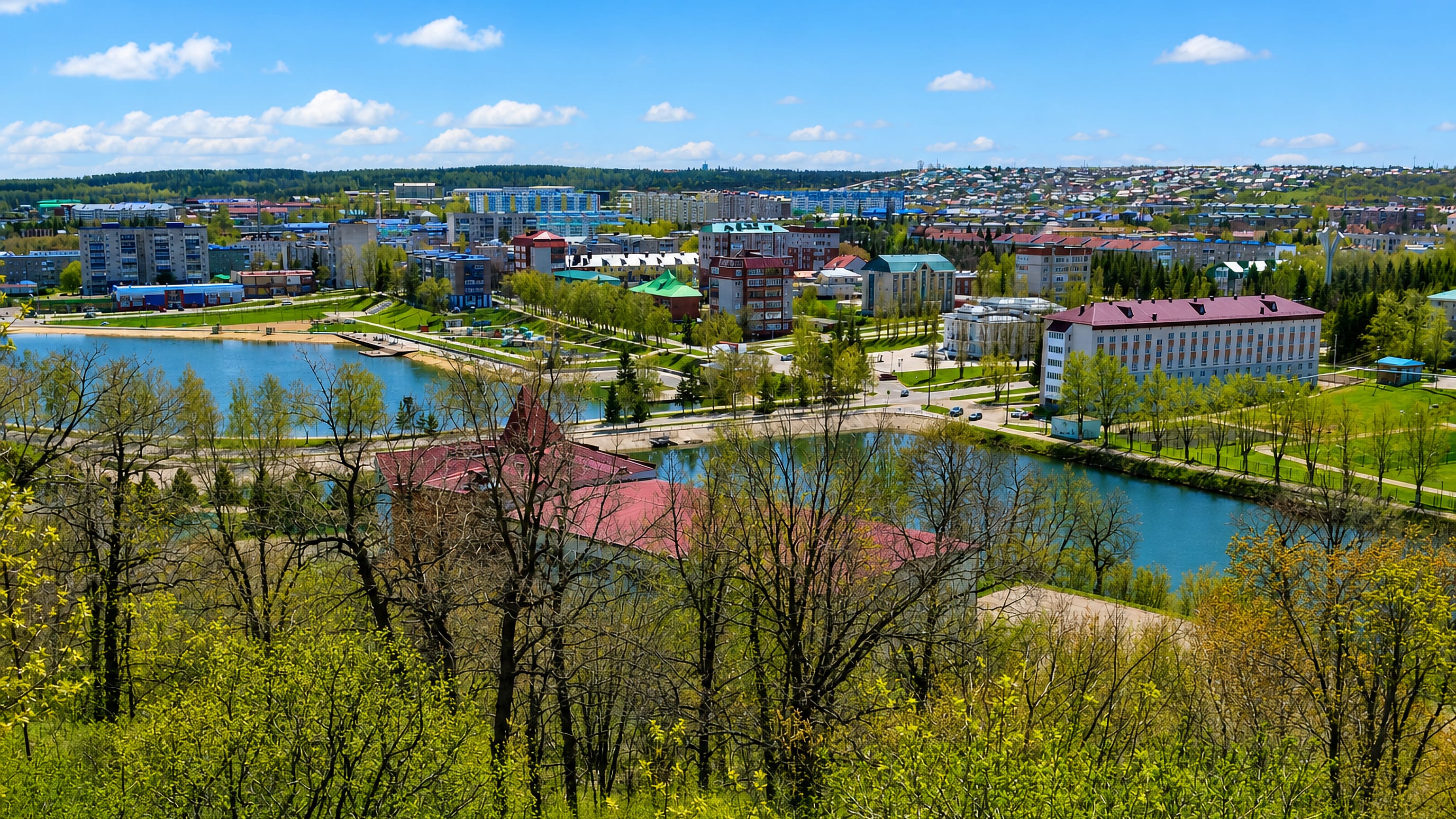 Leninogorsk in Tatarstan seen over spring treetops, with apartment blocks and civic buildings around its ponds.