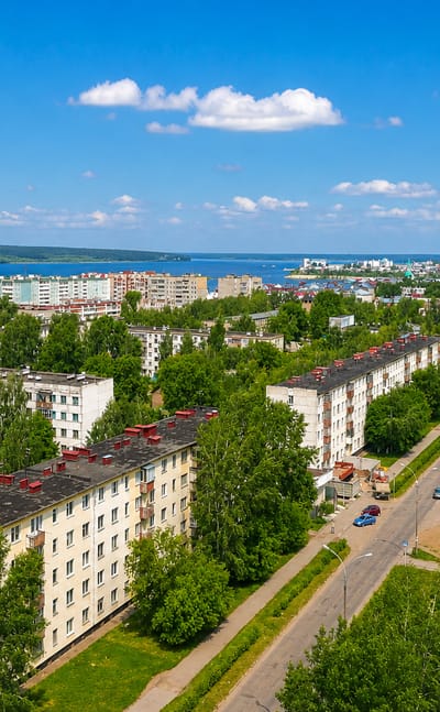 Aerial view over Naberezhnye Chelny's Soviet-era apartment blocks and tree-lined avenues toward the Kama River.