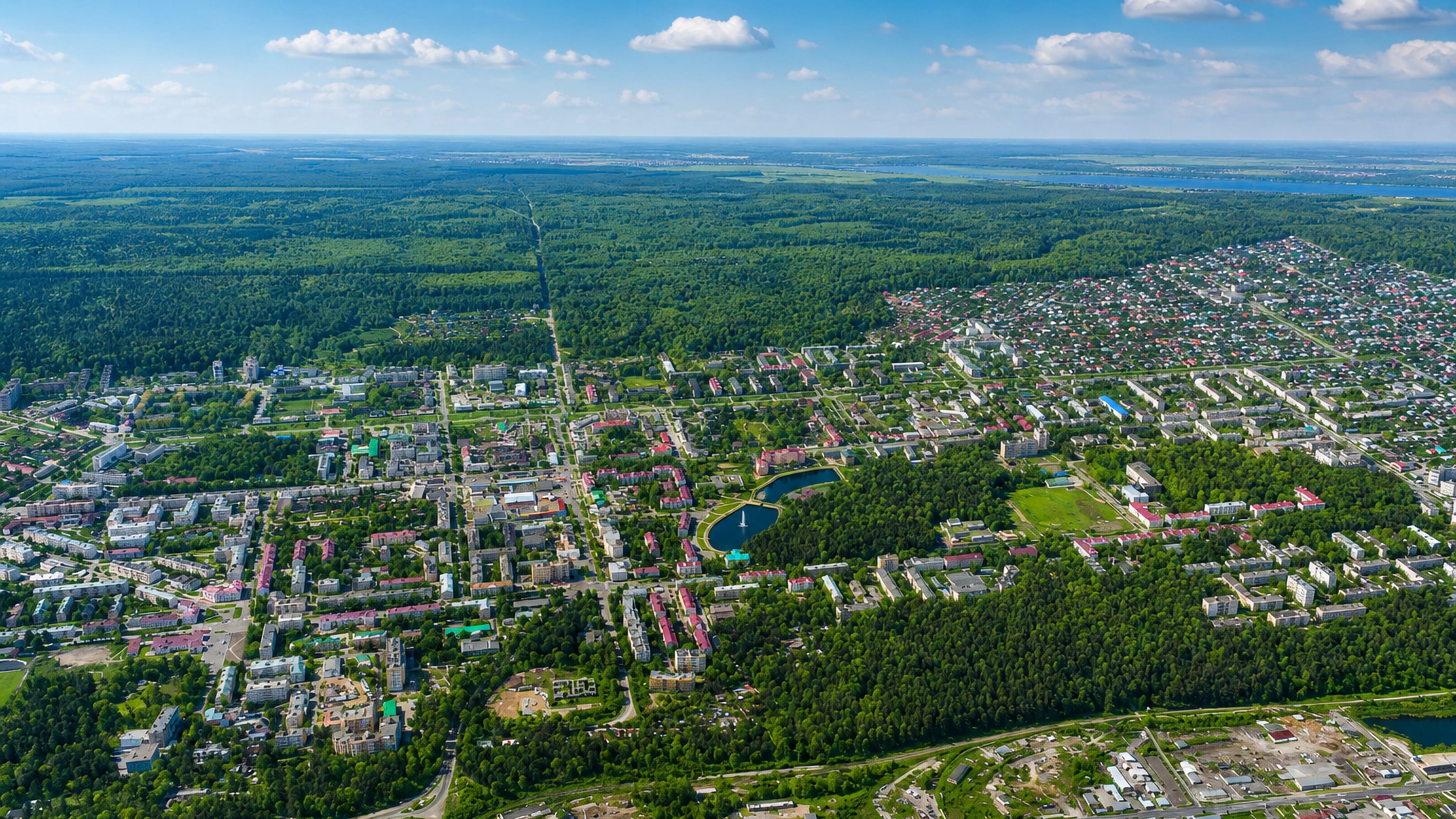 Zelenodolsk, Tatarstan, from the air: low apartment blocks and a park pond enclosed by dense forest.