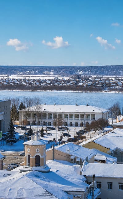 Snow-covered rooftops and the pink Epiphany Cathedral above the Tom River in wintertime Tomsk, Russia.