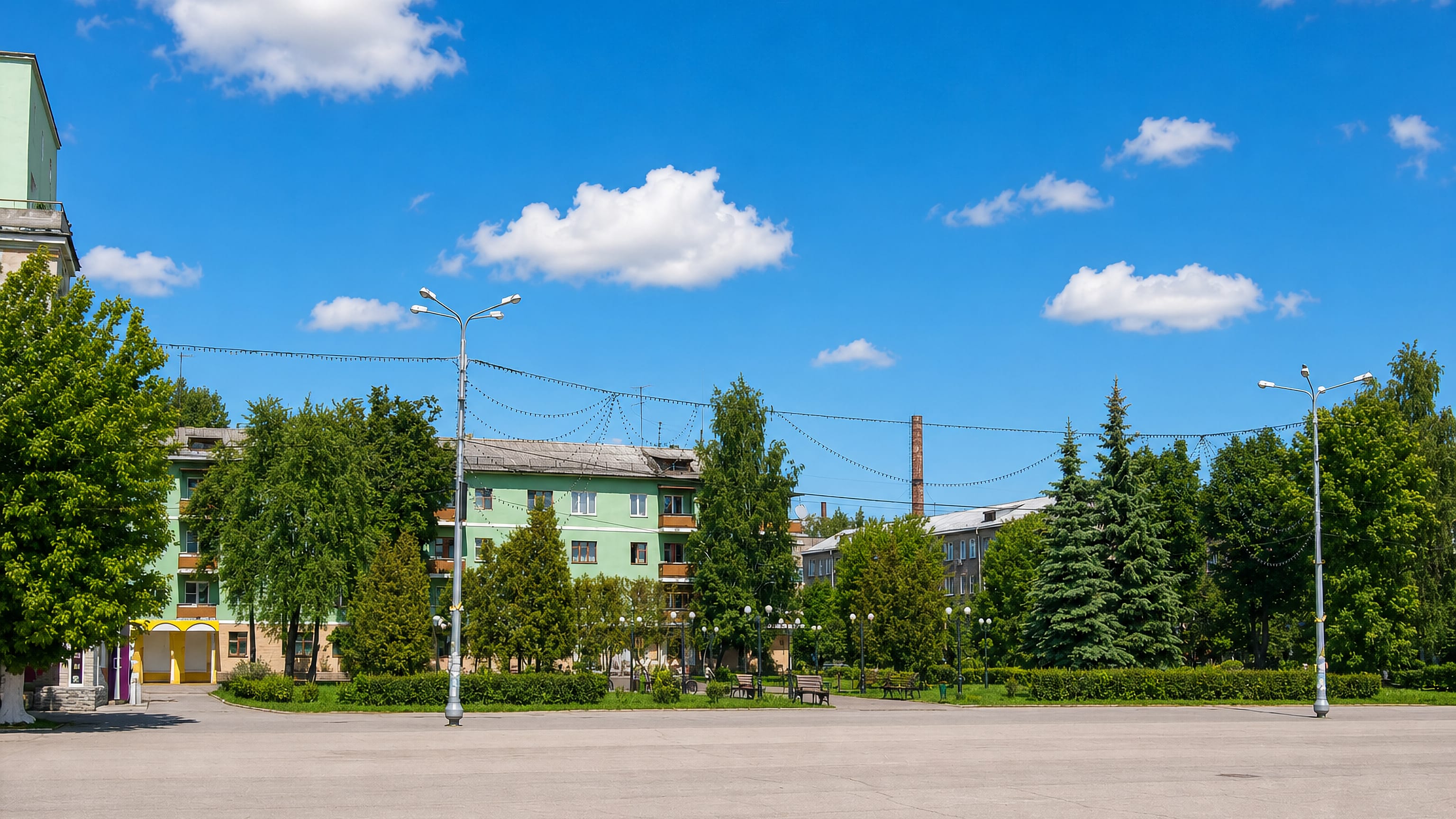 Empty paved square fronting green low-rise apartment blocks and trees in Novomoskovsk, Russia.