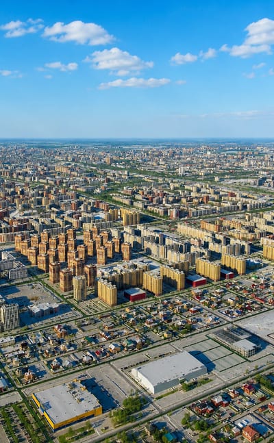 Aerial view of Tyumen's dense mid-rise districts and grid streets stretching to the flat Siberian horizon.
