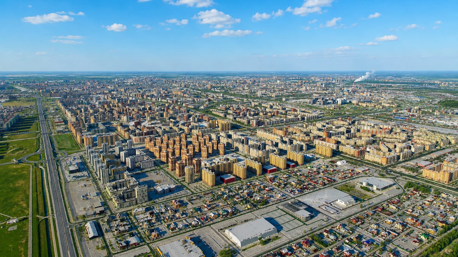Aerial view of Tyumen's dense mid-rise districts and grid streets stretching to the flat Siberian horizon.