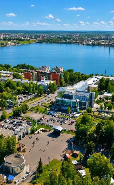 Aerial view of Izhevsk beside its large pond, with a central plaza, apartment blocks and green boulevards.
