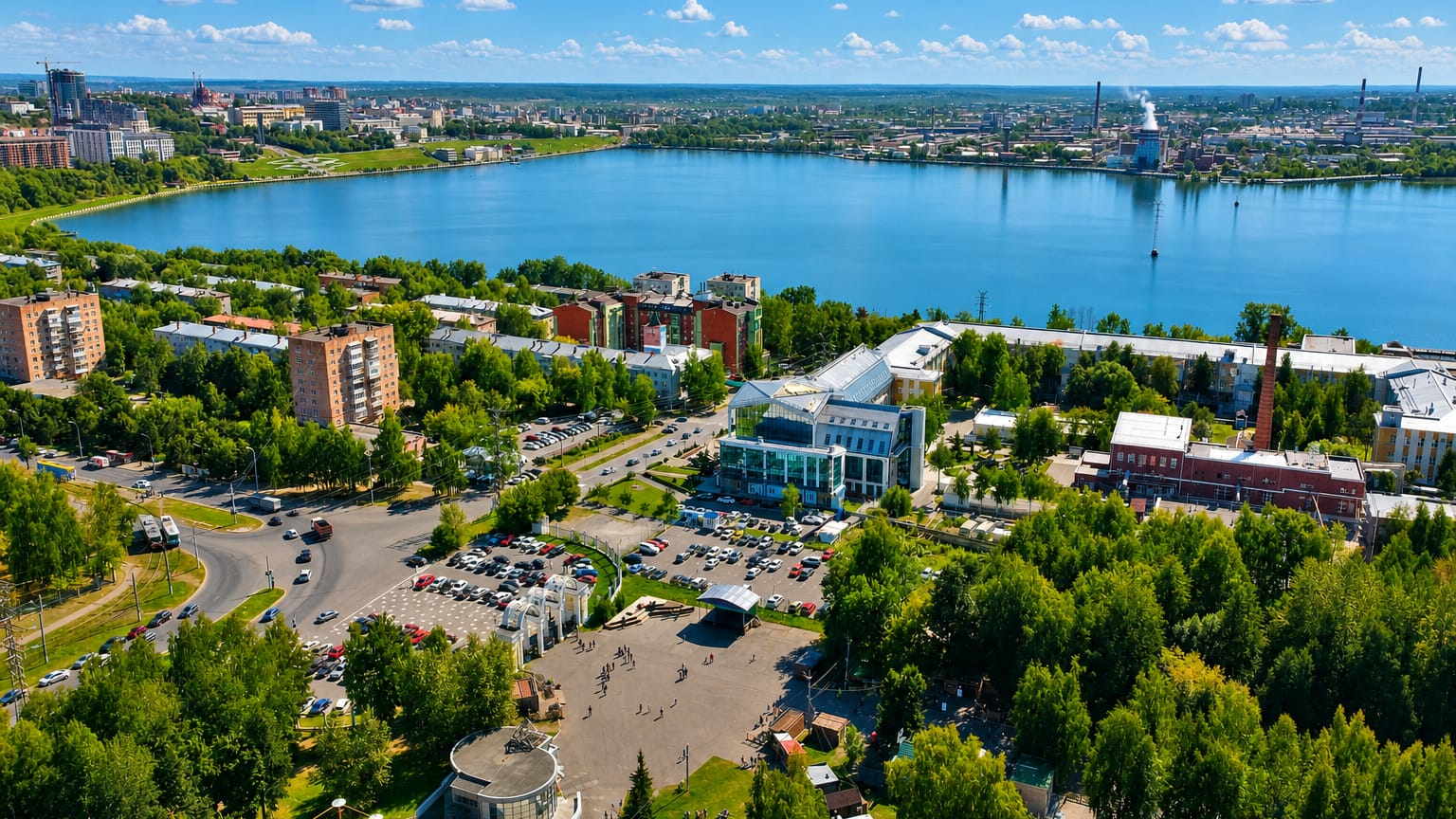 Aerial view of Izhevsk beside its large pond, with a central plaza, apartment blocks and green boulevards.