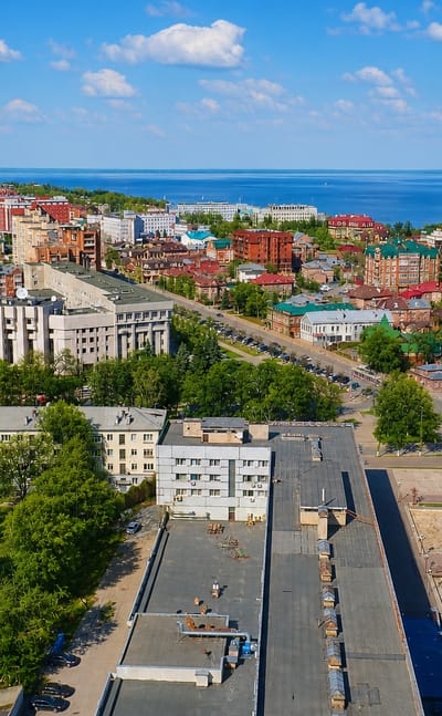 Aerial view of Ulyanovsk with red-roofed buildings and apartment blocks above the wide Volga River.