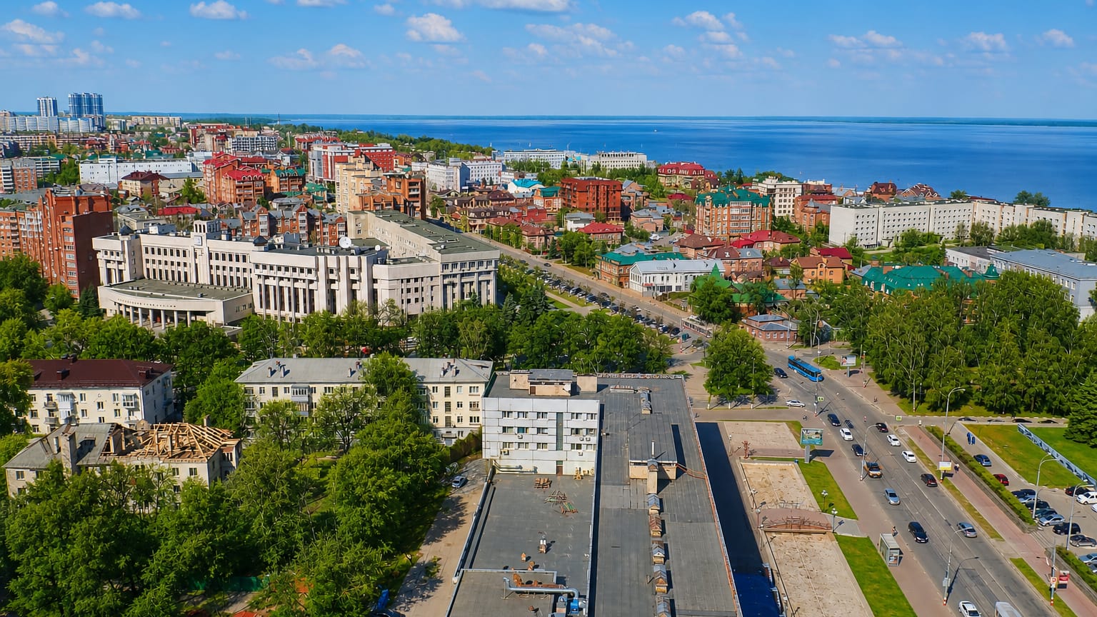 Aerial view of Ulyanovsk with red-roofed buildings and apartment blocks above the wide Volga River.