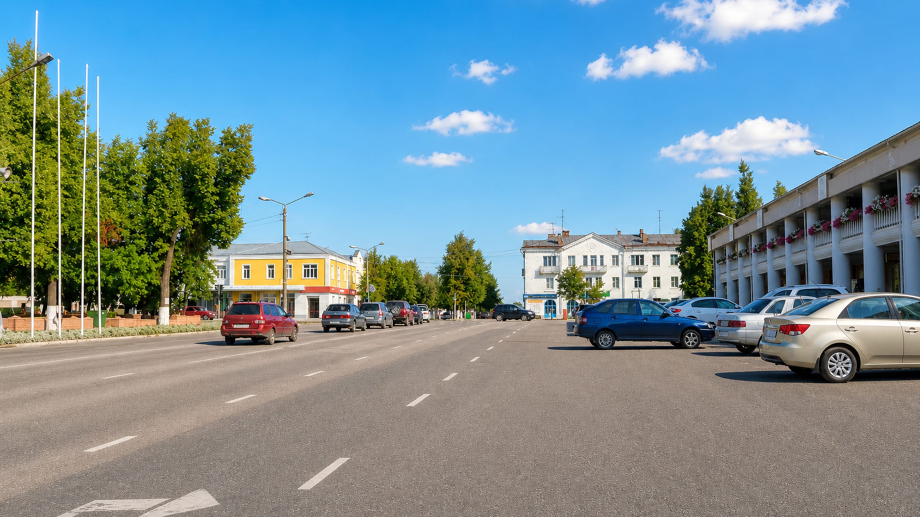 Wide central avenue lined with low pastel buildings and parked cars in Gus-Khrustalny, Vladimir Oblast.