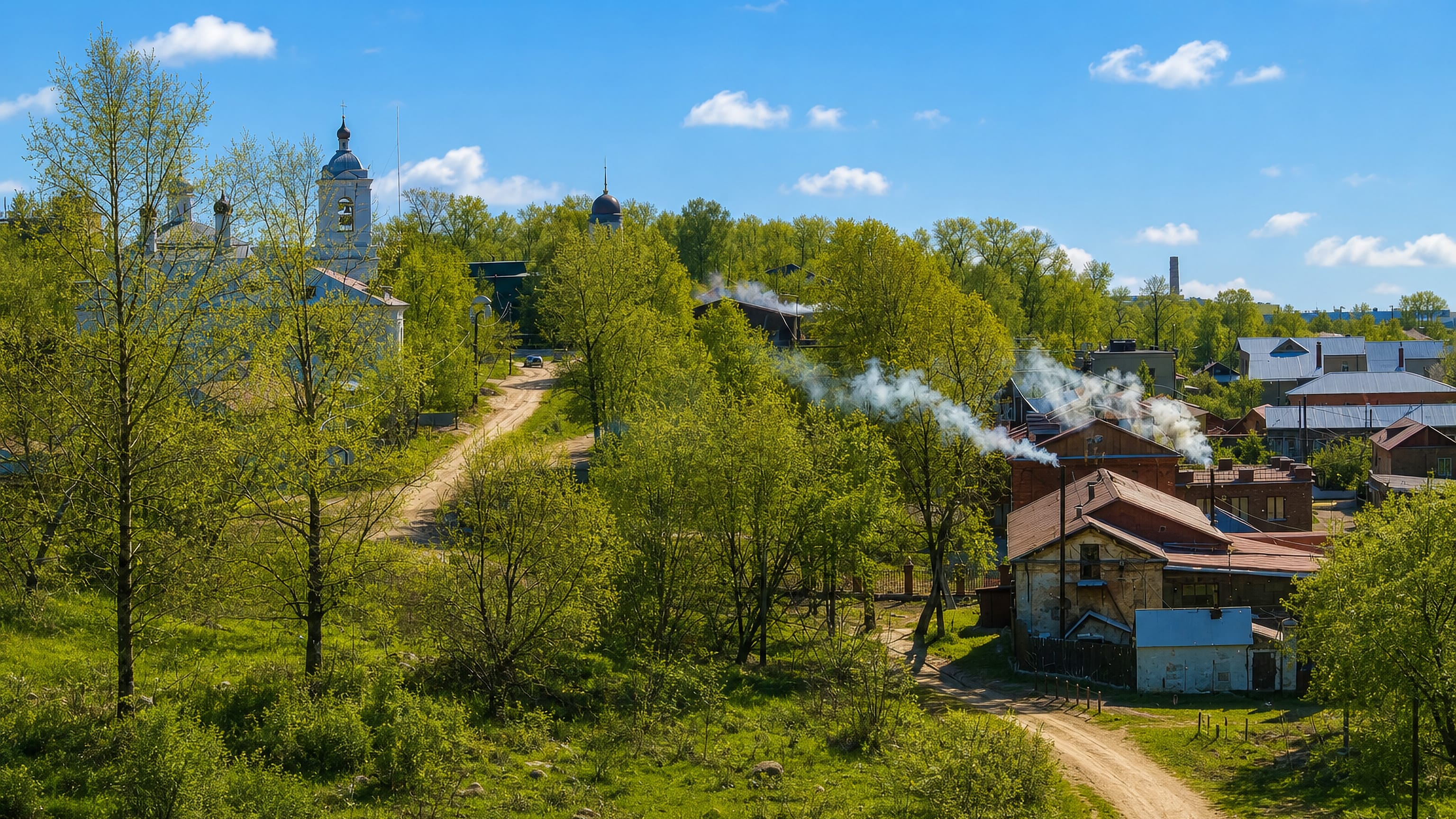 Whitewashed Orthodox church and timber-and-brick houses on a green hillside in Kovrov, Vladimir Oblast.