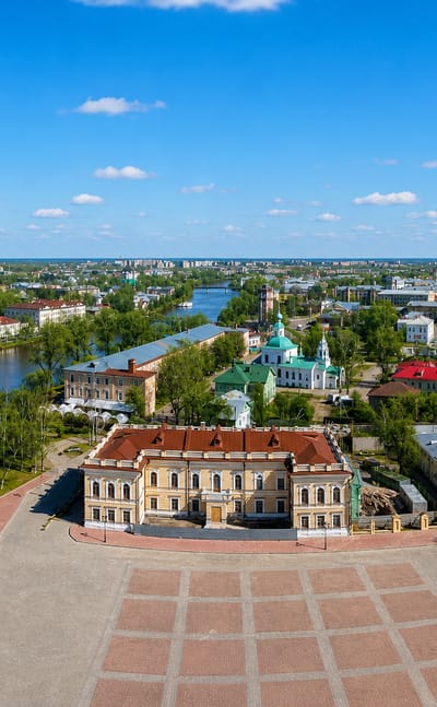 Aerial view of central Vologda with a white bell tower, a classical mansion and a winding river.