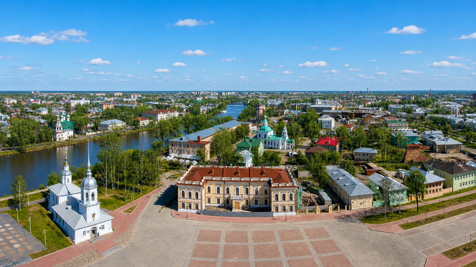 Aerial view of central Vologda with a white bell tower, a classical mansion and a winding river.