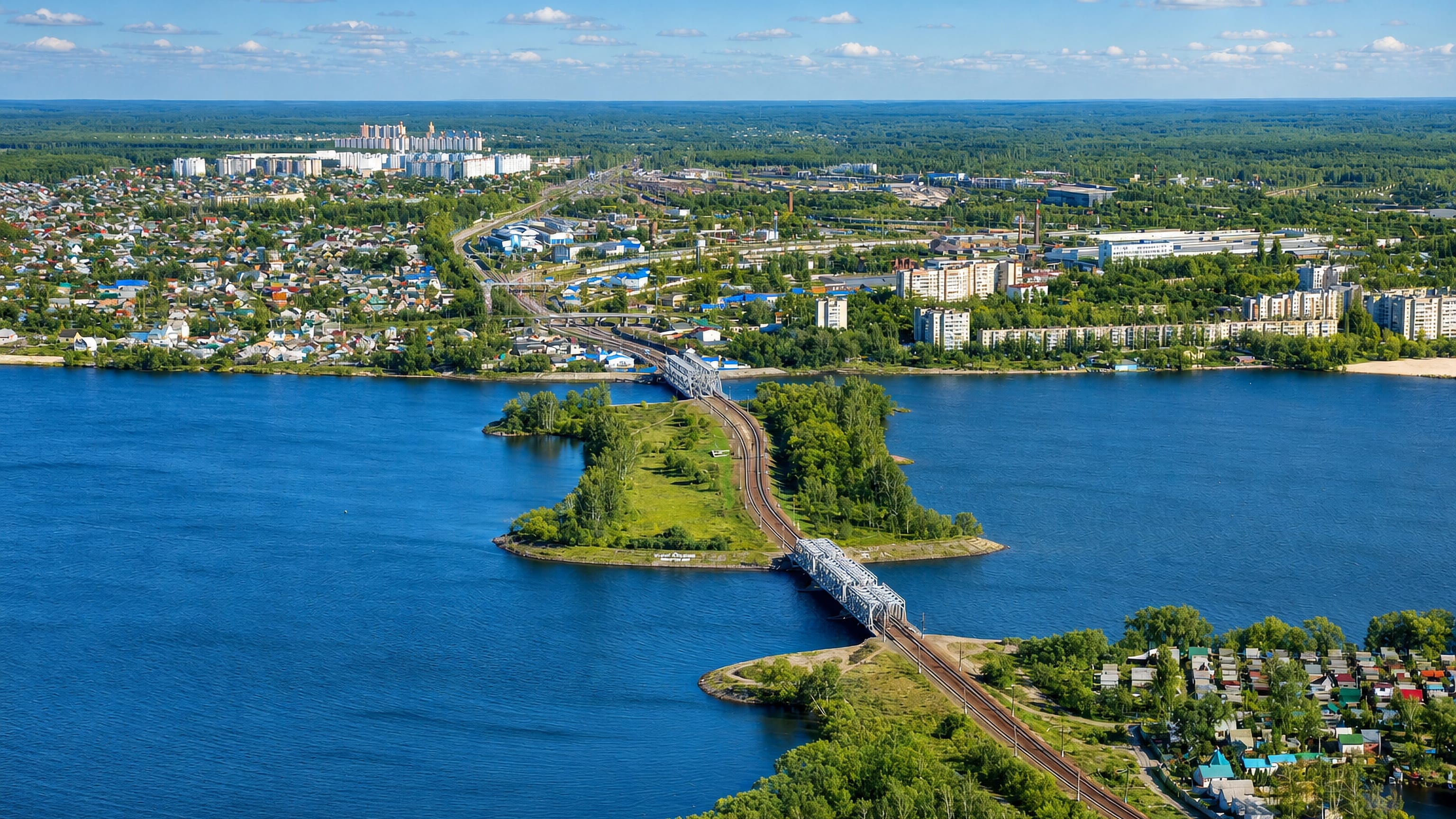 Aerial view of Otrozhka in Voronezh, where a railway bridge crosses the reservoir toward riverside housing.