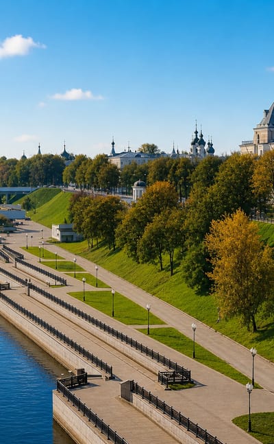 Golden-domed churches along the tree-lined Volga River embankment in Yaroslavl under a clear sky.