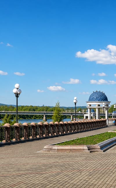 Riverside promenade with a blue-domed rotunda and ornate lamps along the Bira River in Birobidzhan, Russia.