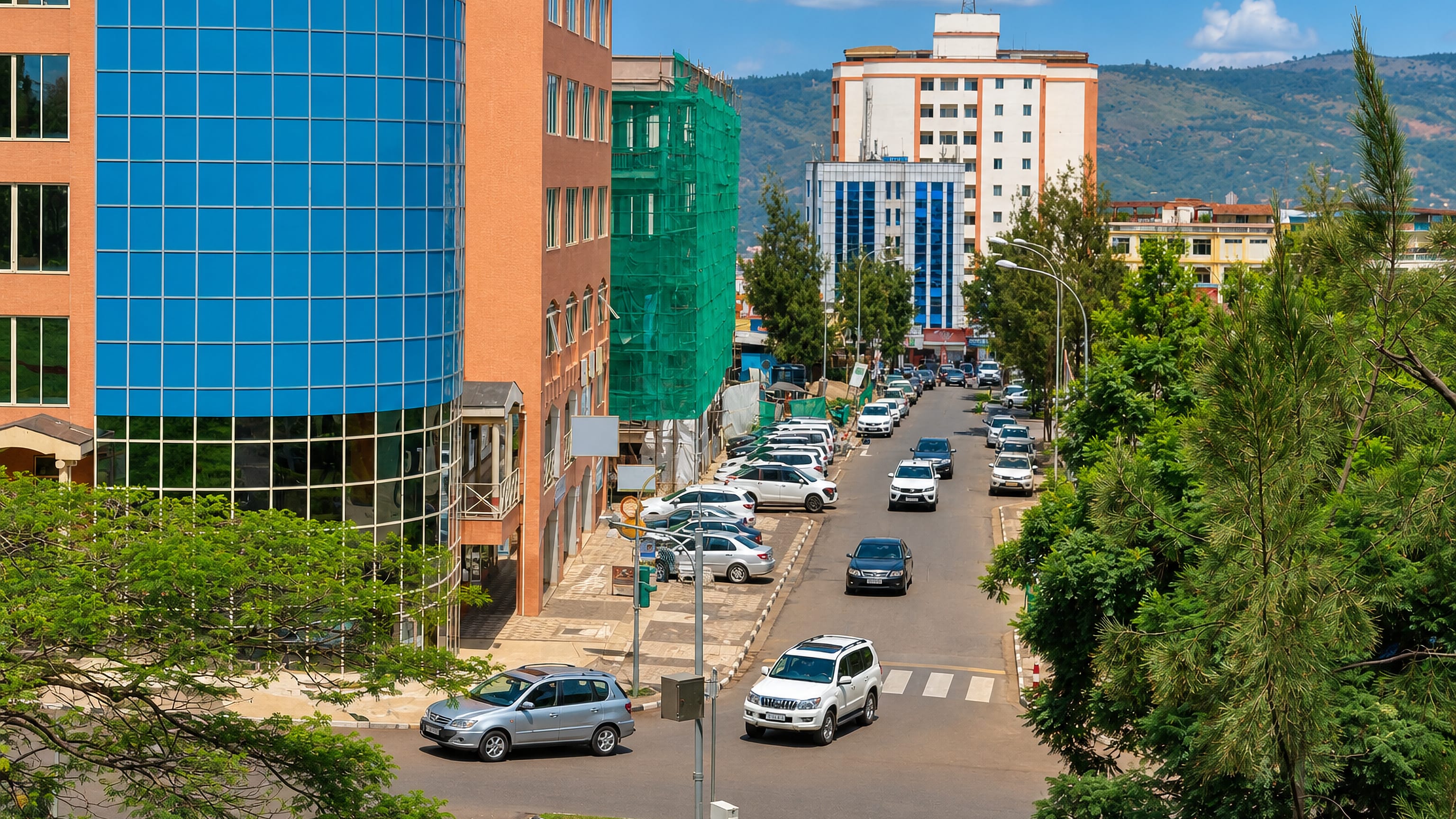 Downtown Nyarugenge in Kigali, with a curved blue-glass office tower above a busy street and green hills beyond.