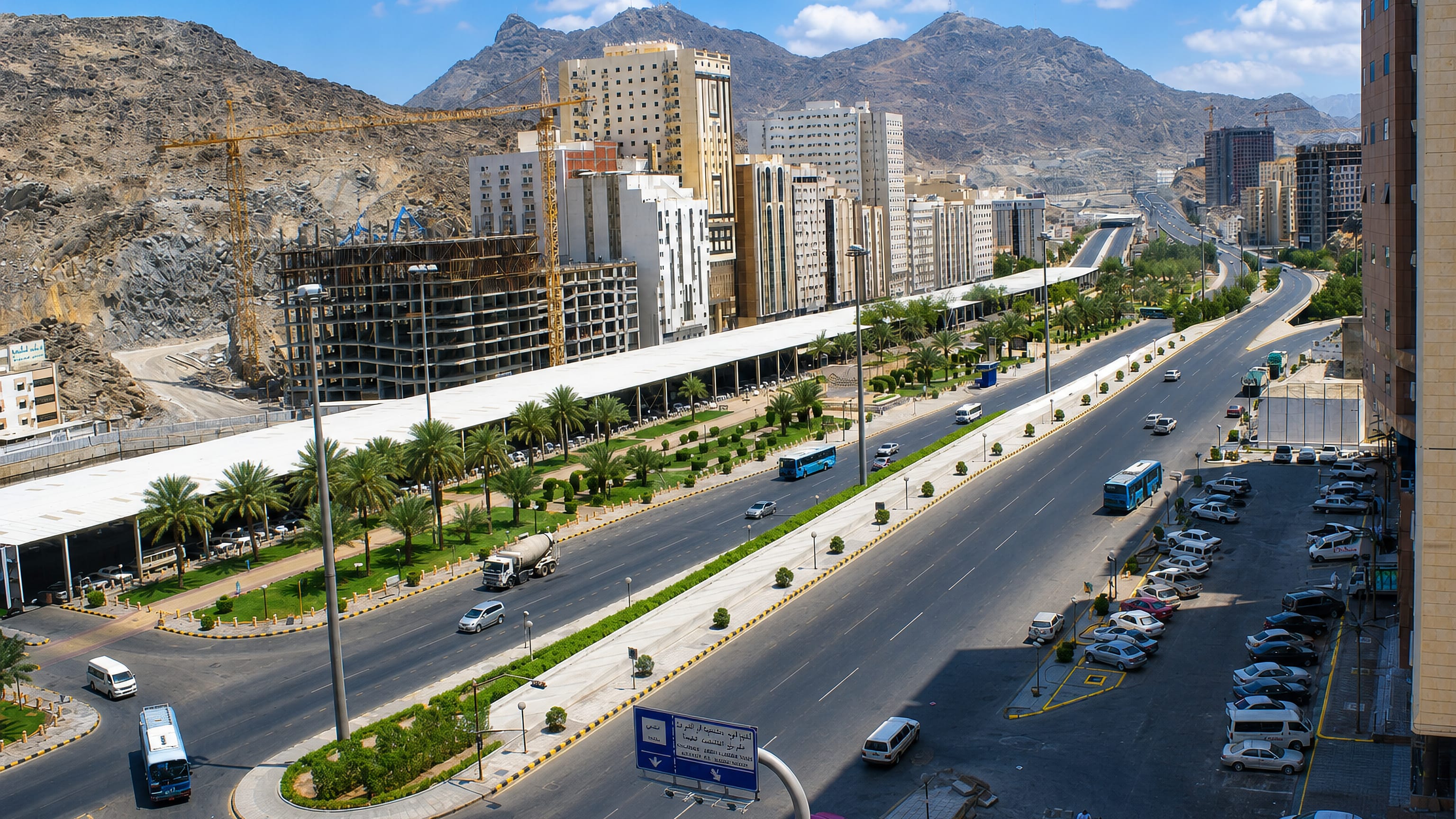 Wide daytime view of Aziziyah, Makkah, with a multi-lane highway, mid-rise buildings and dry rocky mountains in the distance