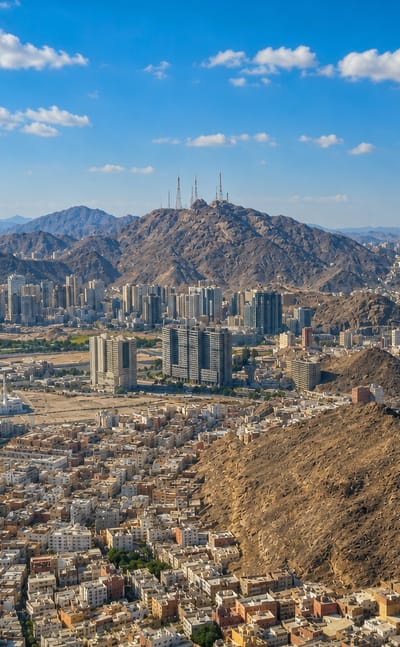 Makkah sprawling across barren mountains with the Makkah Royal Clock Tower rising above the city.