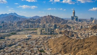 Makkah sprawling across barren mountains with the Makkah Royal Clock Tower rising above the city.