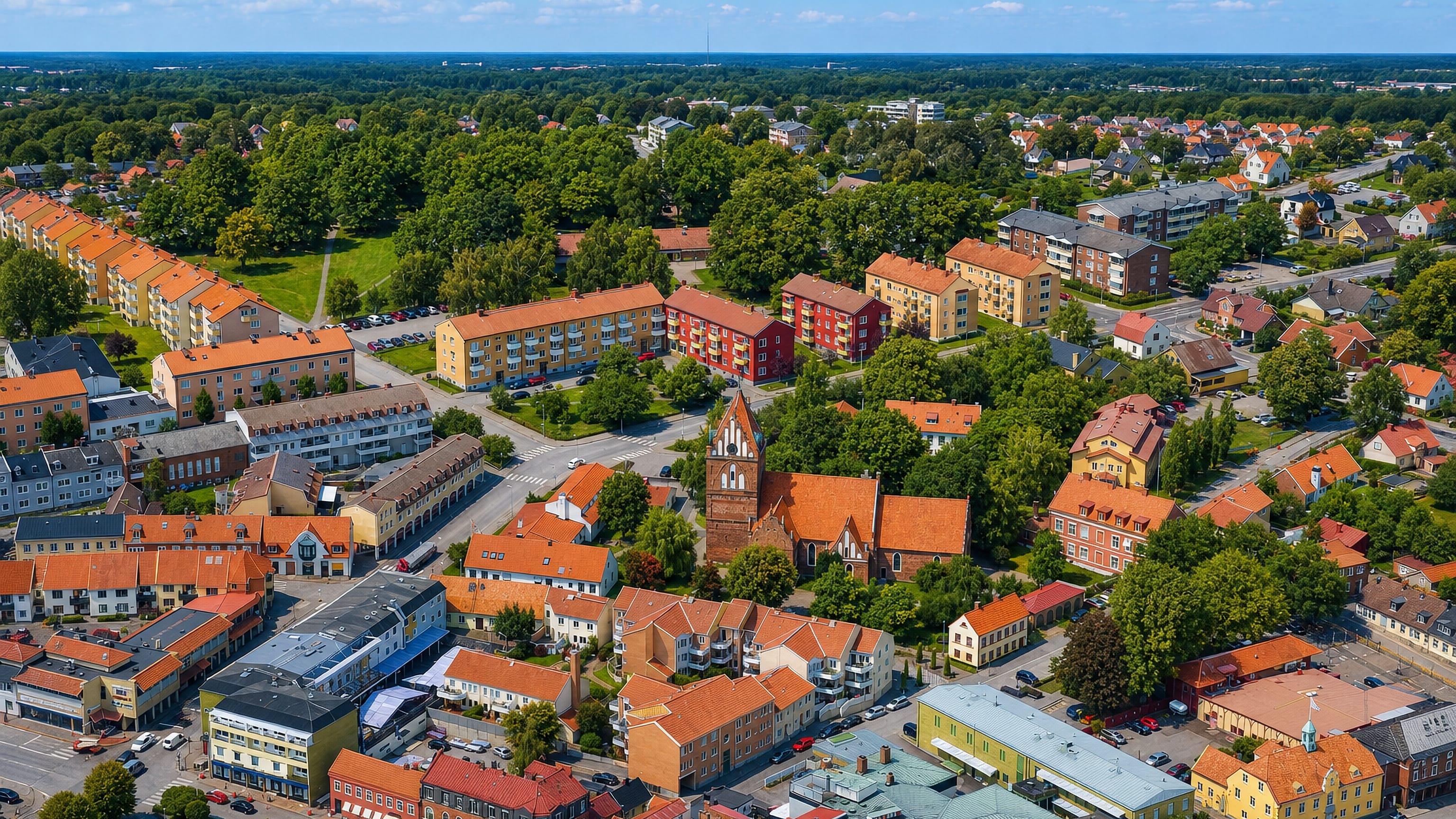 Aerial view of Solvesborg's town centre with its tall brick church tower rising among red-roofed houses.