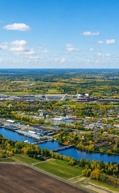 Wide aerial of Avesta, Sweden, stretching along a river through autumn-tinged forest