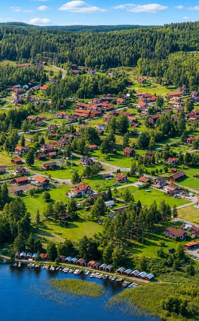 Aerial view of Leksand, Sweden, with Falu-red cottages, green fields and boat jetties along a forested lakeshore