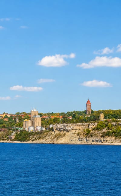 Visby coastline on Gotland, with a red-brick water tower and town rooftops above limestone shore cliffs.