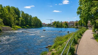 The Atran river running through Falkenberg with rapids, a riverside walking path and town buildings beyond