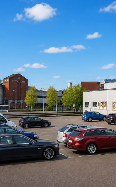 Car park by an ICA supermarket and the paper-mill chimneys of the industrial town of Hyltebruk, Halland.