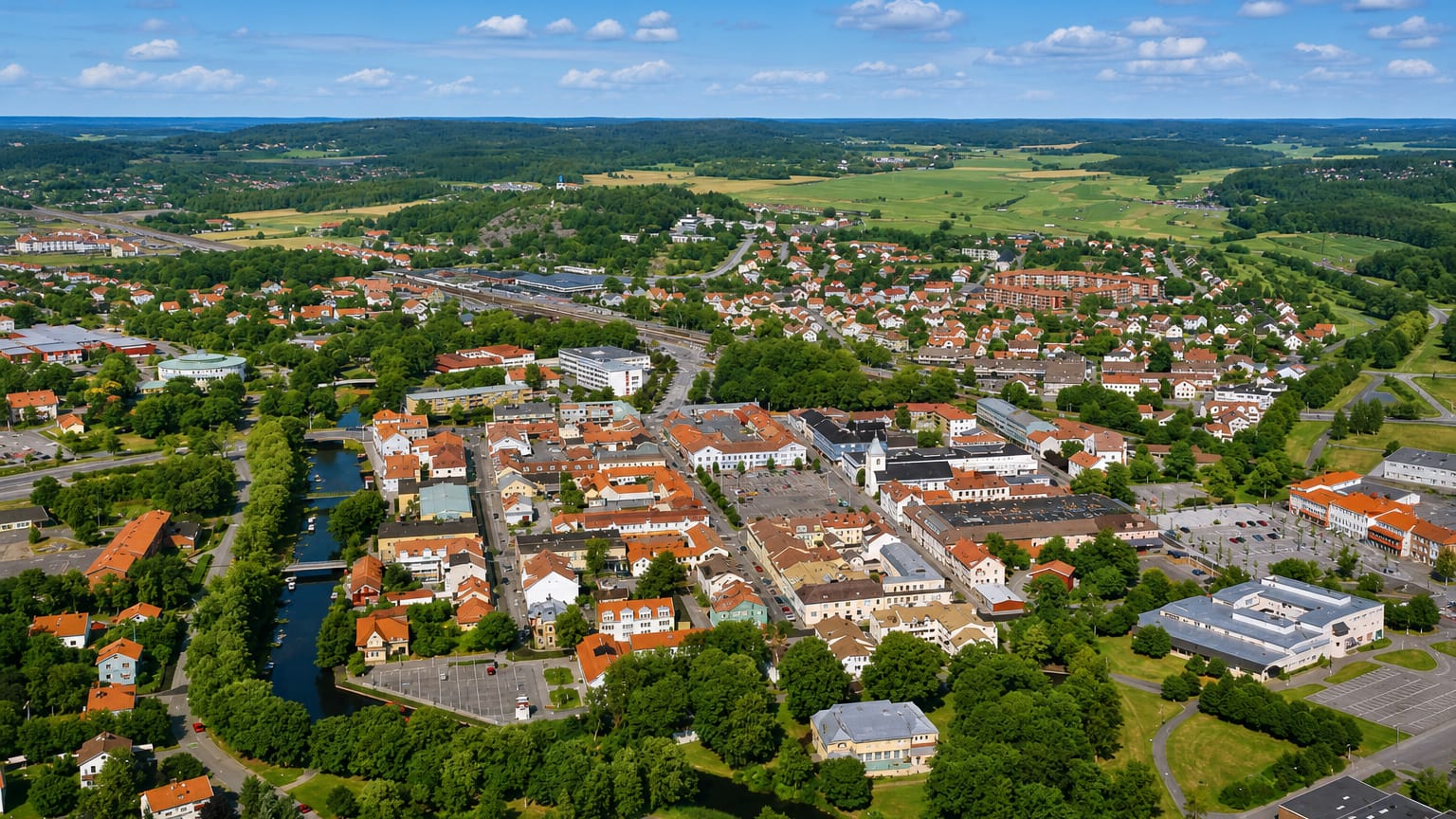 Aerial view of Kungsbacka's red-roofed town centre and winding river amid Halland farmland, Sweden.