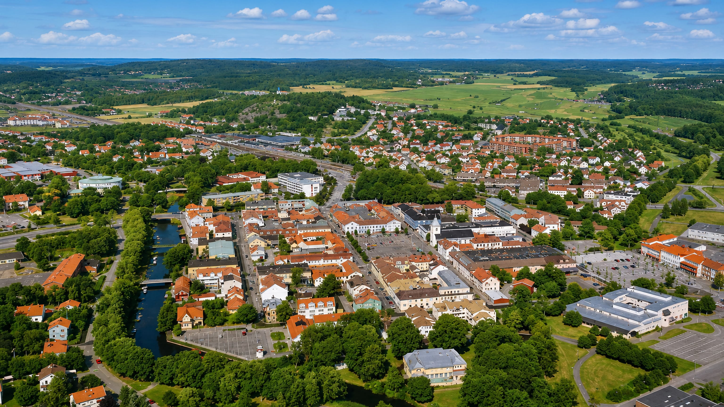 Aerial view of Kungsbacka's red-roofed town centre and winding river amid Halland farmland, Sweden.