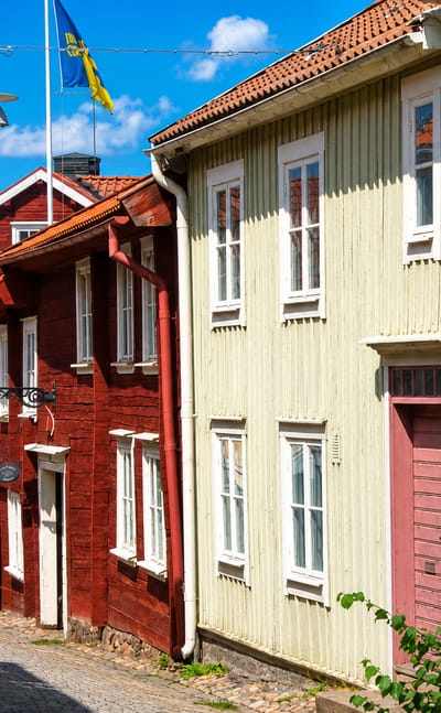 Cobbled lane of red and pale wooden houses in Eksjo's preserved old town with a Swedish flag