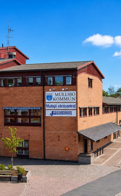 The red-brick Mullsjo Kommun municipal building and health centre on a paved square in Mullsjo, Sweden.