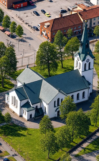 Aerial view of Värnamo church with its green copper spire beside the central town square and surrounding buildings.