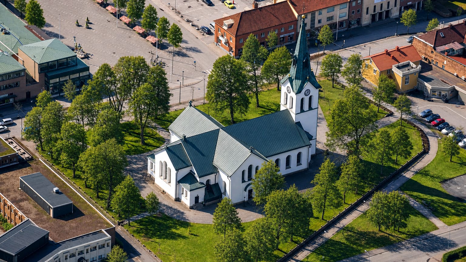 Aerial view of Värnamo church with its green copper spire beside the central town square and surrounding buildings.