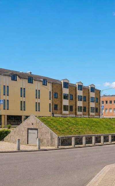 Modern apartment blocks and a grass-covered mound along an empty street in Emmaboda, southern Sweden.