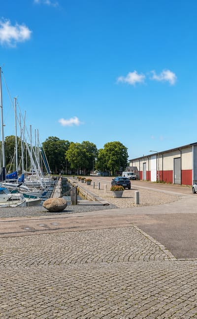 Mörbylånga harbour on Öland with moored sailboats, a red boathouse and a large quayside warehouse, Sweden.