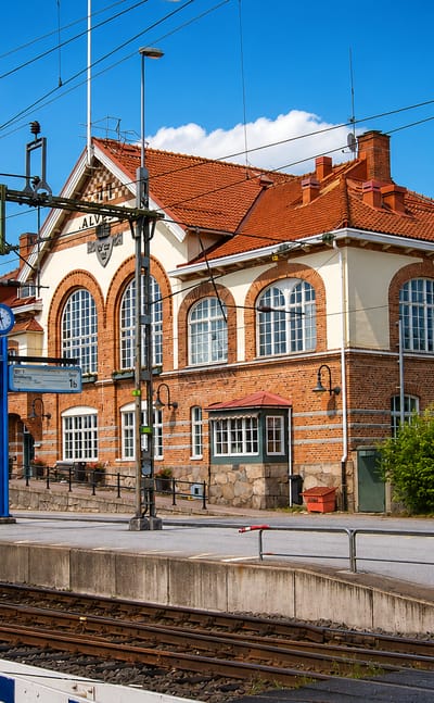 Historic red-brick railway station building signed Alvesta beside the platform and tracks in Alvesta, Sweden