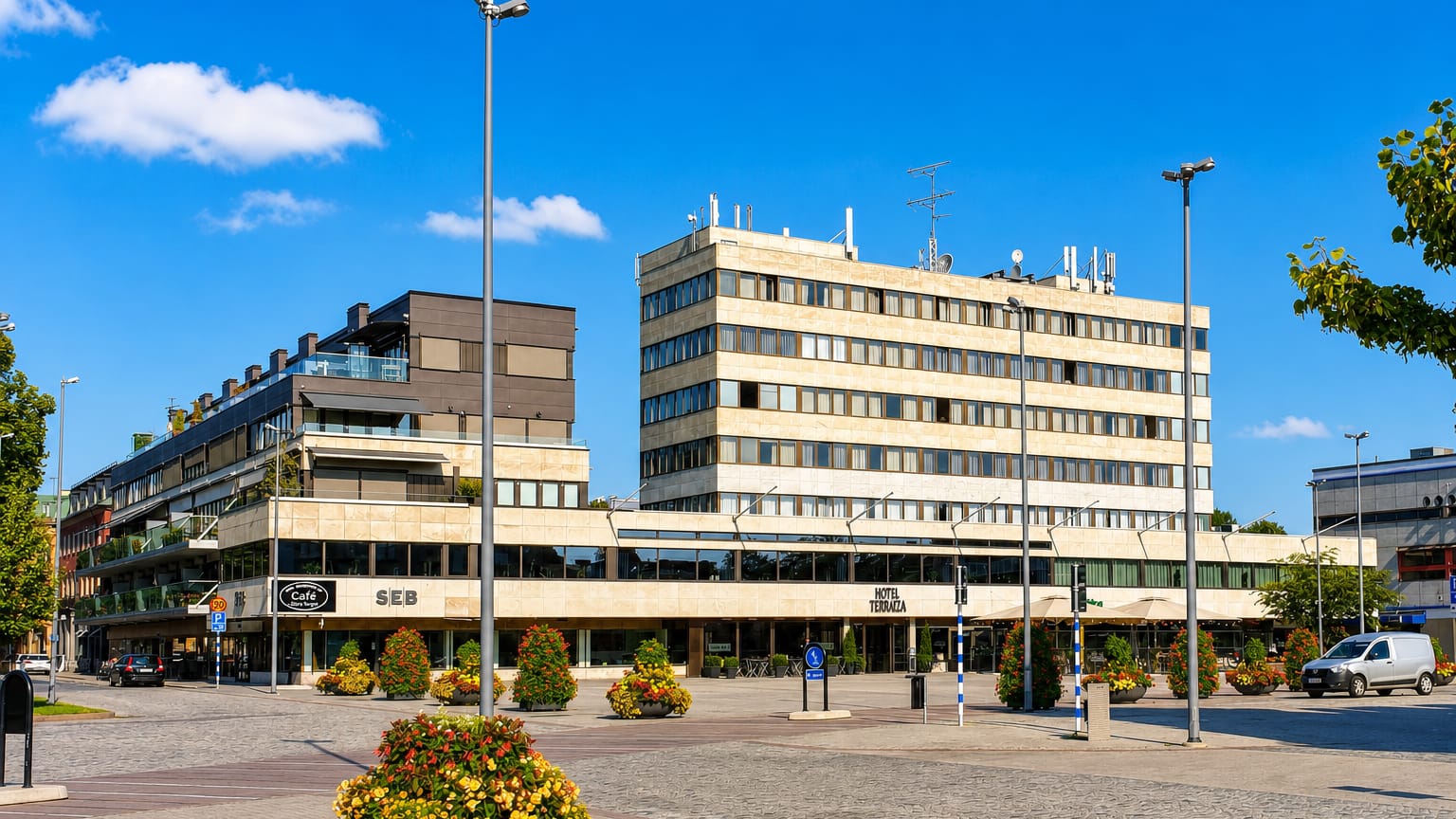 Ljungby's main square with the Hotel Terraza building, an SEB bank and flower planters in sunshine