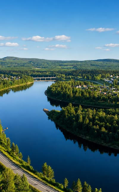 Aerial view of Alvsbyn beside a broad forest-lined river bend in northern Sweden.