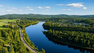 Aerial view of Alvsbyn beside a broad forest-lined river bend in northern Sweden.